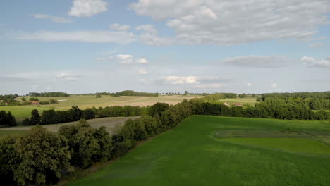 Beautiful-view-over-the-rural-landscape,-flight-over-the-trees,-on-the-horizon-you-can-see-trees-and-blue-sky-with-clouds,-Eastern-Poland-in-warmia-and-masuria