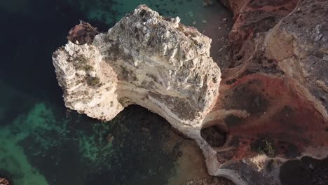 Passing-over-tall-limestone-sea-cliffs-on-Algarve-coast-in-Portugal,-aerial,-birds-eye