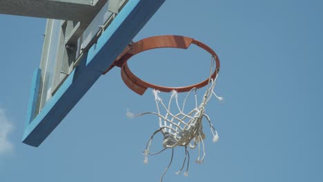 Torn-net-on-an-outdoor-basketball-hoop-moves-in-the-wind
