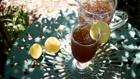tall-glass-of-ice-tea-with-lemon-in-outdoor-summer-garden-wind-blowing-leaves-shadows