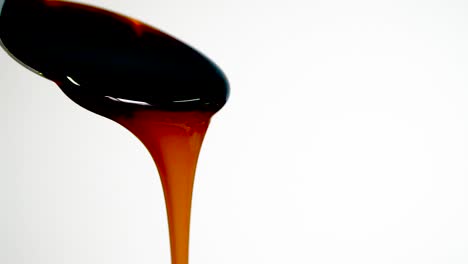 Molasses-pours-from-spoon,-slow-motion,-close-up