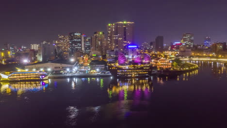 Hyperlapse-drone-tracking-shot-scanning-the-Saigon-waterfront-showing-major-tourist-attractions-and-key-infrastructure-of-the-docks-and-financial-center-at-night-with-reflections-in-the-Saigon-river