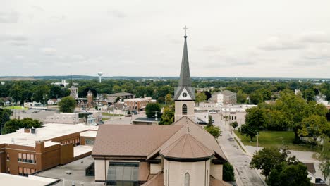 parallax-drone-video-of-catholic-church-on-a-cloudy-summer-day-surrounded-by-the-city-of-Little-Chute,-Wisconsin