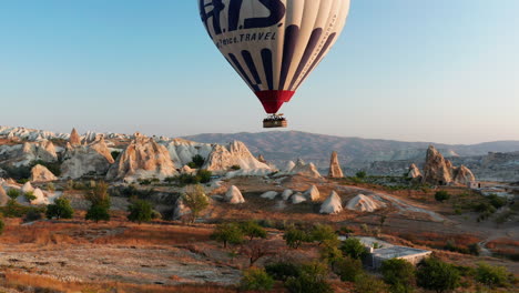 Hot-air-balloon-flying-over-the-arid-landscape-of-Goreme-Cappadocia,-Turkey