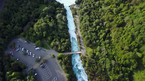 Aerial-shot-of-white-and-blue-rapids-on-river-next-to-a-forest-tilting-up-to-the-horizon
