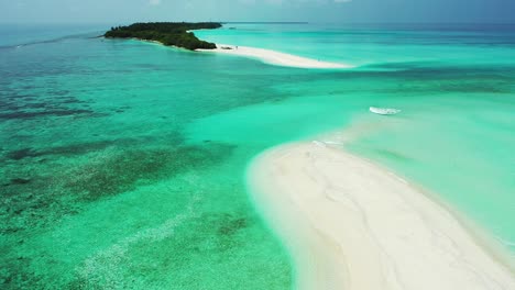 Peaceful-great-turquoise-lagoon-with-different-coral-patterns-surrounding-white-sandy-stripe-and-low-lying-tropical-island-in-Fulhadhoo,-Maldives