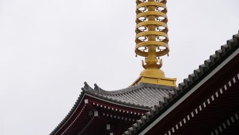 Tilting-shot-of-a-golden-finial-at-the-top-of-Senso-ji-Temple-building