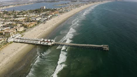 Aerial-shot-tilting-down-to-a-pier-at-Pacific-Beach,-San-Diego