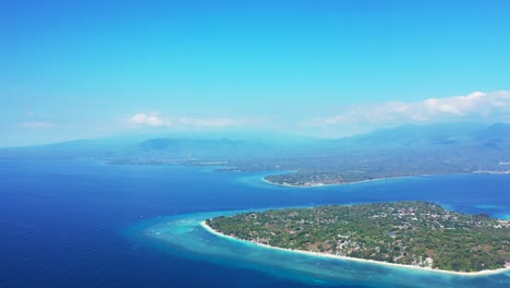 Blue-seascape-at-fogy-morning,-light-blue-sky-with-white-clouds-over-low-lying-tropical-islands-surrounded-by-calm-blue-sea-in-Indonesia