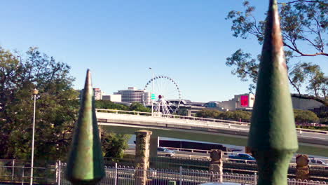 Close-up-of-green-iron-fence-with-The-Wheel-of-Brisbane-in-distance