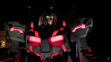 Panning-shot-of-Unicorn-Gundam-Statue-illuminated-at-night-in-Odaiba,-Tokyo