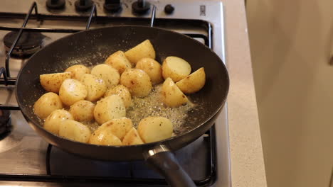 Small-potatoes-being-sautéed-in-a-pan-with-bubbling-butter-and-garlic-on-a-gas-stove