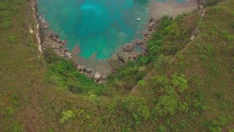 Birdseye-Aerial-View-of-Rocky-Coast-Of-Tropical-Island-and-Aqua-Blue-Lagoon