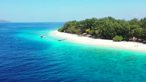 Touring-boats-anchored-on-blue-turquoise-lagoon-waiting-close-to-white-exotic-beach-for-tourists-to-explore-new-secret-places-around-tropical-islands-in-Indonesian-coastline