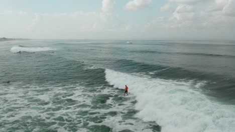 Male-Surfer-on-Waves-of-Indian-Ocean-Surfing-Near-Coast-of-Bali-Island-Indonesia,-Aerial