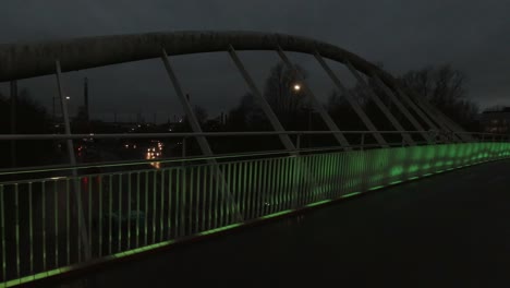 Slow-pan-right-across-Steve-Prescott-colourful-illuminated-bridge-crossing-in-town-urban-scene-at-night