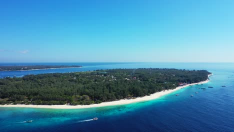 Idyllic-tropical-islands-for-holiday-with-white-beach-and-lush-vegetation-surrounded-by-blue-turquoise-sea-where-boats-sailing-around-bay-in-Indonesia