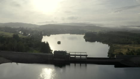 An-aerial-view-of-Lairg-dam-on-a-misty,-sunny-morning