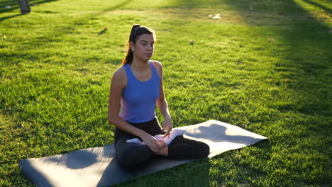 A-fit-young-woman-sitting-in-lotus-position-during-meditation-in-the-park-at-sunrise-to-improve-her-mental-health