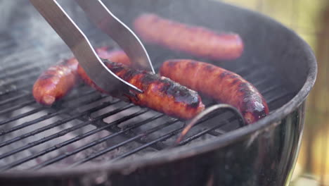 Slow-Motion-of-Tongs-Picking-Up-a-Gristly-Sausage-From-Smokey-BBQ-Grill