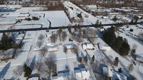 A-slowly-moving-forward-snowy-aerial-flyover-of-a-suburban-Michigan-residential-neighborhood-on-a-sunny-winter-day