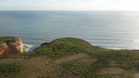 Aerial-view-flying-over-a-large-hill-toward-the-ocean