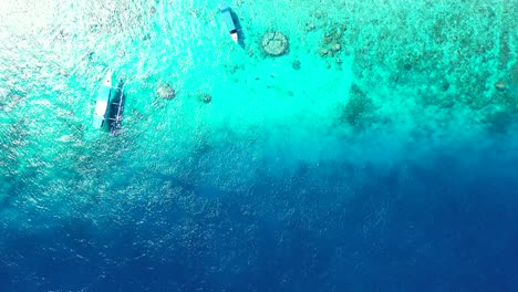 Traditionelle-Balinesische-Boote-Ankern-Auf-Blau-türkisfarbenem-Meerwasser-über-Wunderschönem-Meeresgrund-Mit-Felsen-Und-Kieselsteinen