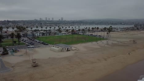 Cloudy-Morning-West-Coast-Beach-with-Green-Park-and-Palm-Trees-Rising-Aerial-View-revealing-marina-and-city