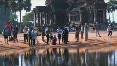 Medium-Close-Shot-of-Tourist-Taking-Photos-by-the-Water-Across-from-Angkor-Wat