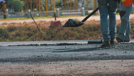 Construction-Workers-Manually-Flattening-a-Newly-Laid-Road-Surface-Ready-for-the-Steam-Roller
