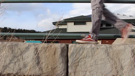 Man-walks-across-low-cement-wall-in-pair-of-red-Vans-sneakers