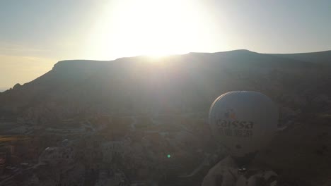 Luftaufnahme-Von-Heißluftballons,-Die-Bei-Sonnenuntergang-über-Einer-Berglandschaft,-Kappadokien,-Türkei,-Fliegen