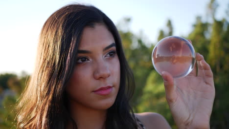 A-pretty-woman-in-a-mystical-fantasy-land-casting-a-spell-or-enchantment-and-staring-with-curious-eyes-at-a-magic-crystal-ball-CLOSE-UP