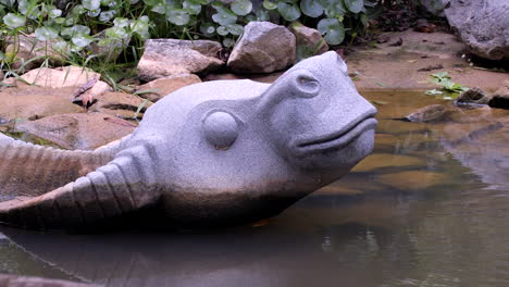 A-stone-bull-sculpture-submerged-in-water-and-displayed-in-the-Garden-By-The-Bay-park-in-Singapore---Close-up