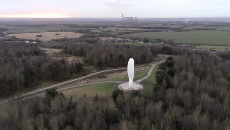 Aerial-view-above-landmark-Dream-giant-head-monument-in-British-countryside-woodland-parkland-forest