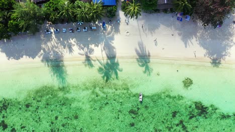 Beautiful-lagoon-with-coral-reefs-and-algae-washing-white-sandy-beach-with-people-sunbathe-on-sunbeds-in-Thailand