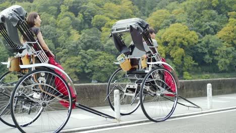 Tourists-sitting-in-a-riskshaw-on-a-bridge-in-Kyoto,-Japan-soft-lighting-slow-motion-4K
