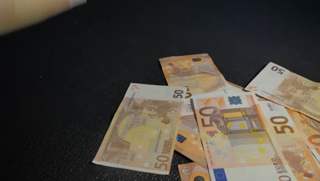 Ein-Statischer-Haufen-Von-Euro-Banknoten,-Die-Auf-Eine-Schwarze-Oberfläche-Fallen