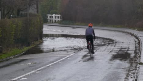 Cyclist-and-van-on-stormy-flash-flooded-road-corner-bend-UK