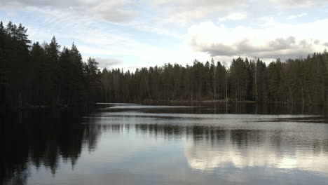 Luftaufnahme-Einer-Drohne-Tief-über-Der-Reflektierenden-Oberfläche-Eines-Ruhigen-Sees-Luukinjarvi,-Teilweise-Sonnig,-Frühlingstag,-In-Luukki,-Espoo,-Finnland