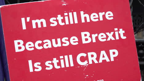Un-Cartel-Rojo-De-Protesta-Dice-&quot;todavía-Estoy-Aquí-Porque-El-Brexit-Sigue-Siendo-Una-Mierda&quot;