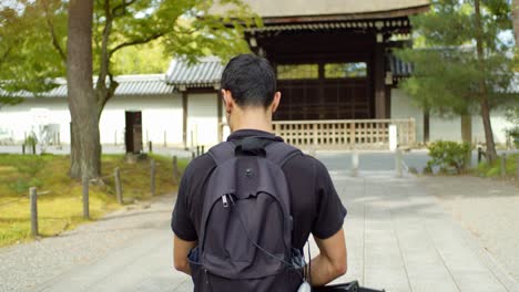 Person,-Die-Auf-Einen-Hölzernen-Toreingang-Zugeht,-Umgeben-Von-Bäumen-Im-Hintergrund-In-Kyoto,-Japan,-Sanfte-Beleuchtung-4K