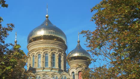 View-of-orthodox-St-Nicholas-Naval-Cathedral-golden-domes-and-crosses-on-blue-sky-in-sunny-autumn-day-at-Karosta,-Liepaja,-wide-shot