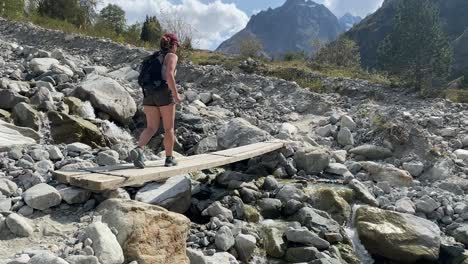 Slow-motion-shot-of-a-young-woman-crossing-over-a-small-bridge-in-a-beautiful-rocky-terrain