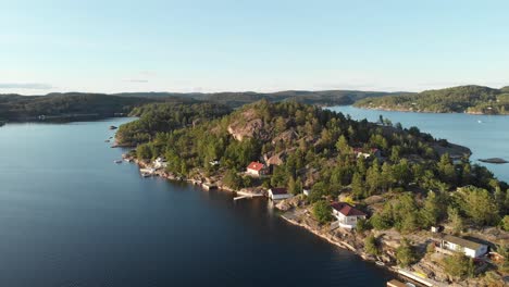 Tranquil-fishing-village-cabins-on-Norwegian-fjord-islet,-aerial-view