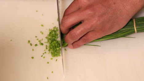 Chef-Chopping-Green-Chives-For-Sushi-At-The-Kitchen---overhead-slowmo-shot