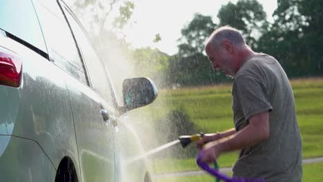 Slow-motion-of-man-washing-his-car-and-dancing-with-the-hose-and-soapy-rag