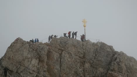 Alpine-Climbers-reaching-the-Summit-Cross-of-the-Zugspitze,-Germay's-Highest-Mountain,-Alps,-Bavaria,-Germany
