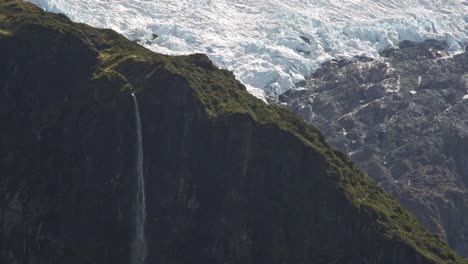 Ein-Langer-Wasserfall-Aus-Brautschleier-Fällt-über-Ein-Tal-Mit-Gletschereis-Im-Hintergrund