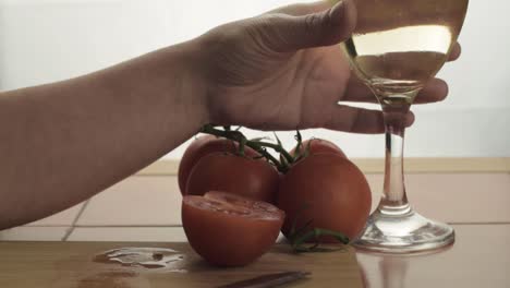 Hand-holding-glass-of-white-wine-snacking-on-fresh-vine-tomatoes